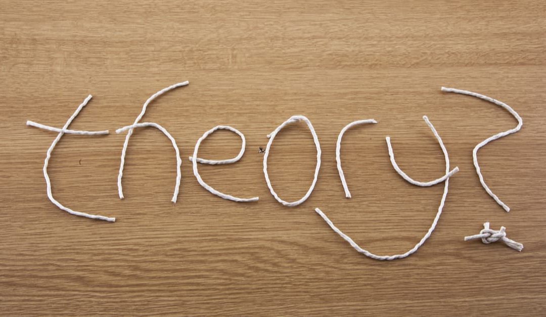 string theory depicted by the word theory spelled out in pieces of string on a wooden table