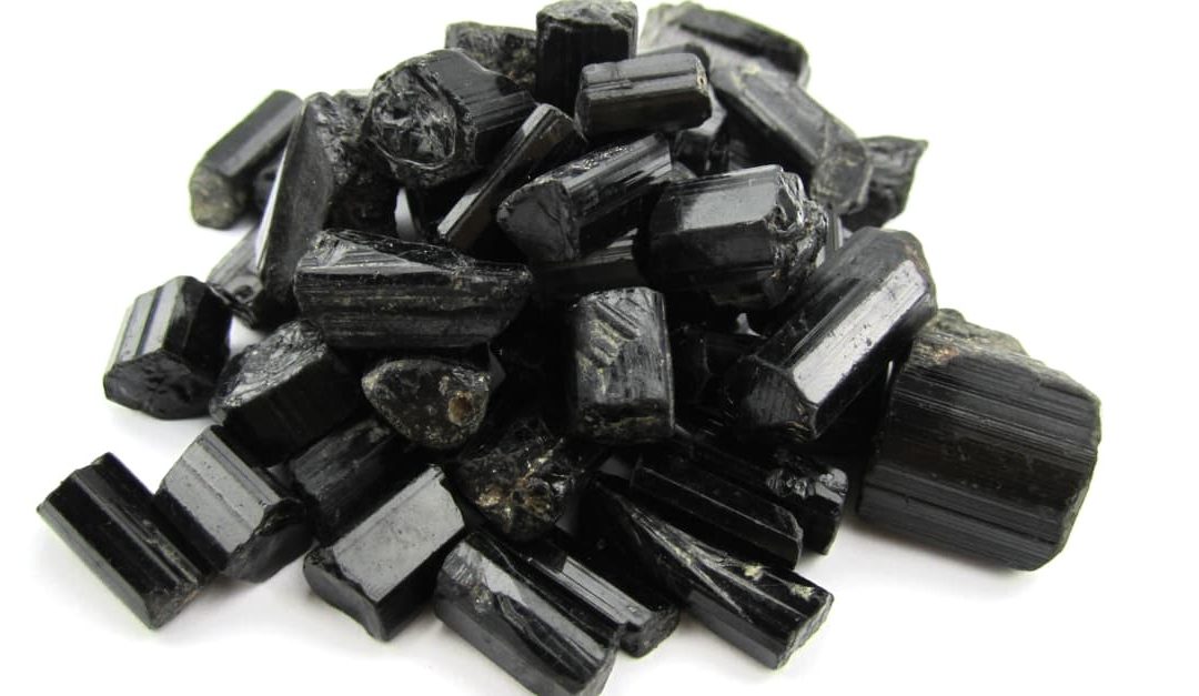 a small pile of uncut black tourmaline on a white background