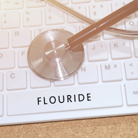 Word Flouride on white keyboard and stethoscope on table