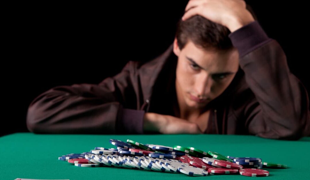 a young man holds his head in despair whilst gambling
