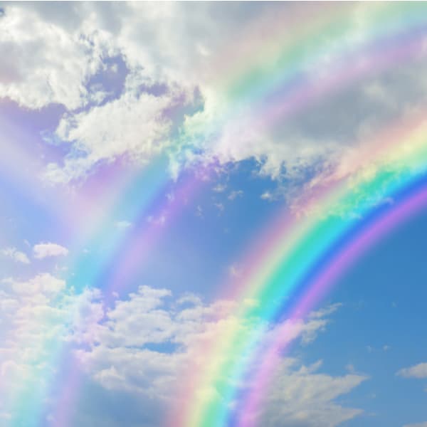 blue sky with pretty clouds, bright sun shining down and a large double rainbow arcing across