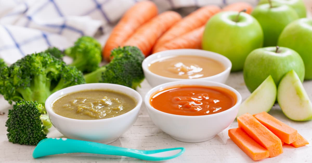 Baby food. Various bowls of fruit and vegetable puree with ingredients for cooking on wooden table