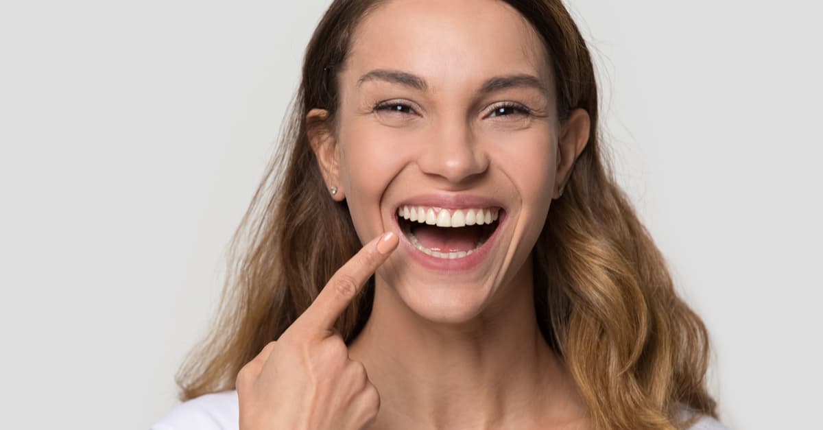 woman pointing to teeth happy that they are healthy