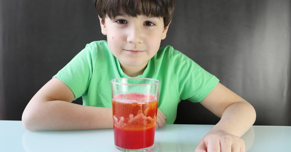 Child doing an experiment, a lava lamp with water, oil, dye, and effervescent tablet
