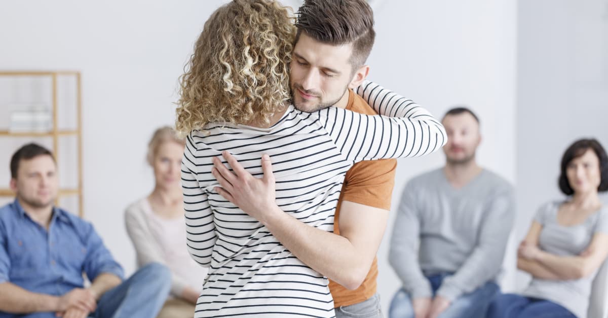 Man and woman hugging at support group