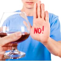 hand up saying no to glass of alcohol