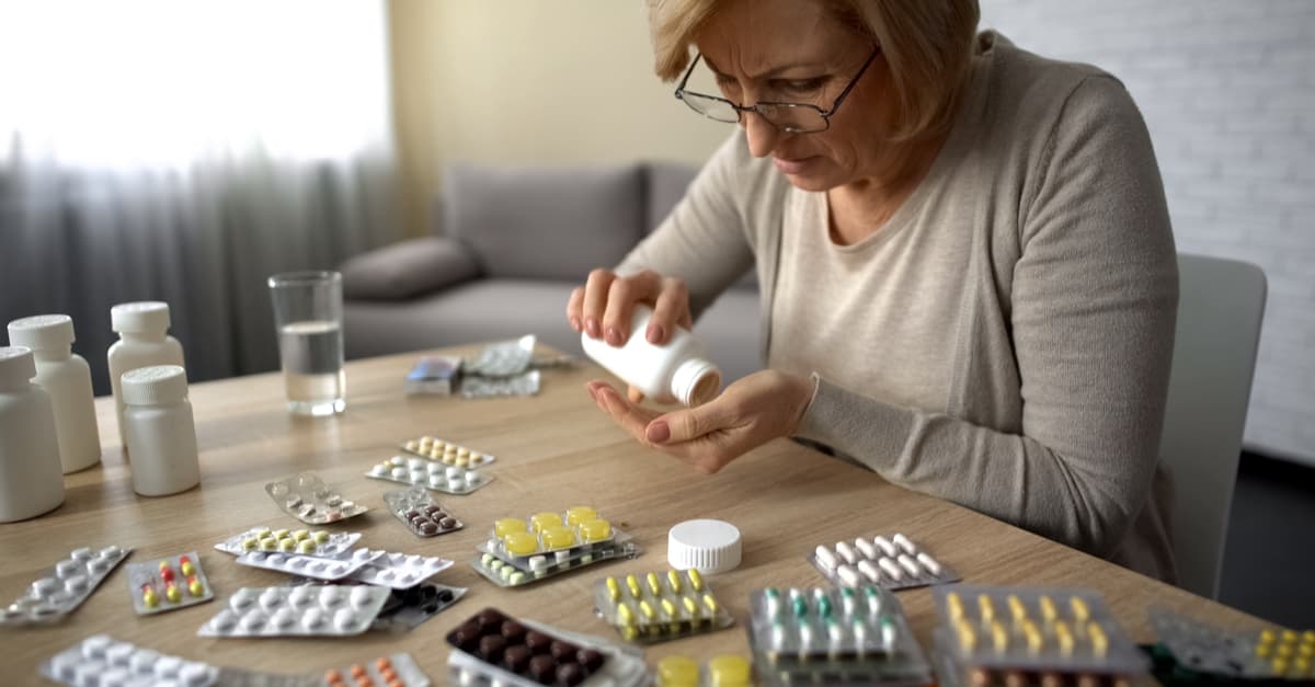 Woman at a table full of prescribed medicines