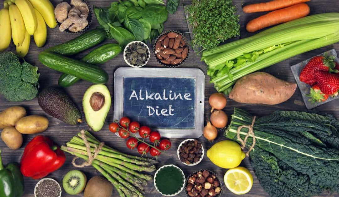 An array of alkaline foods around a chalkboard with the words Alkaline Diet