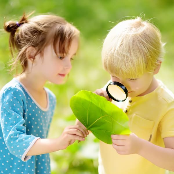Kids exploring nature with magnifying glass.