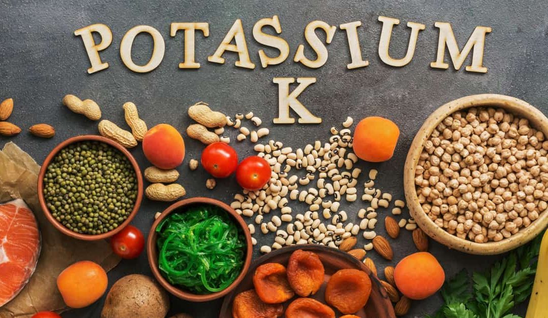 Foods rich in potassium, salmon, legumes, vegetables, fruits on a dark background.