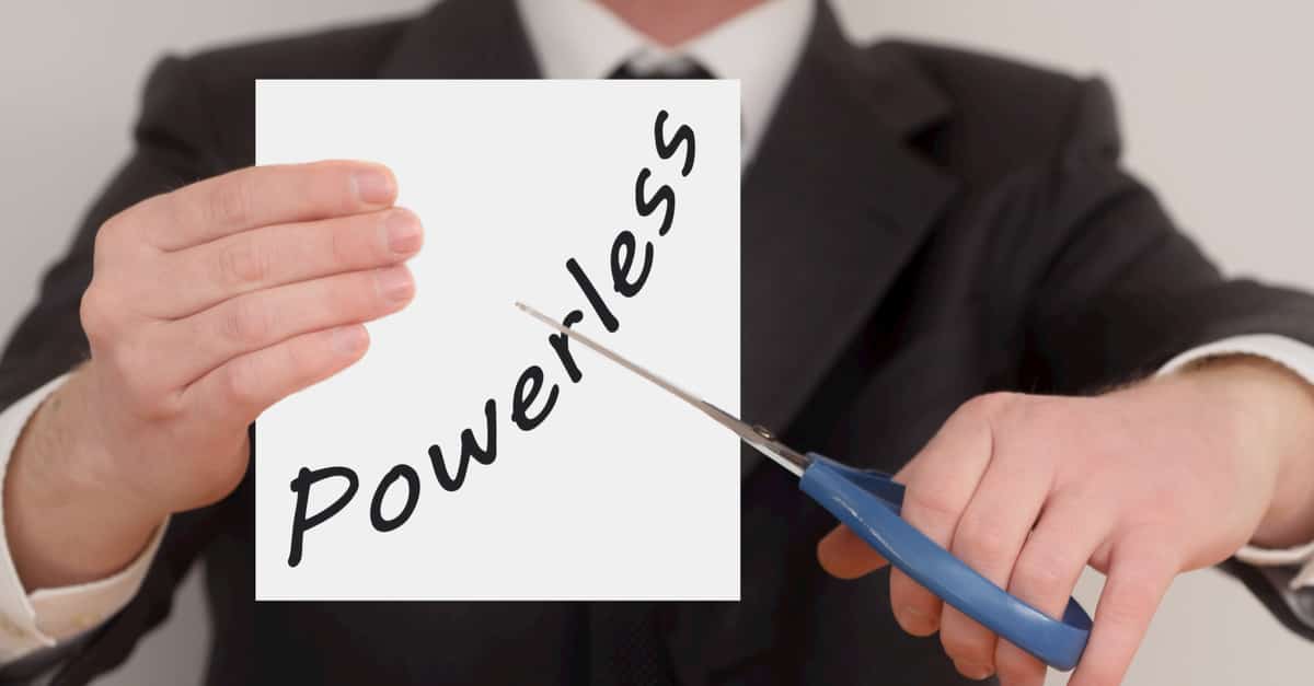 Powerless, man in suit cutting text on paper with scissors