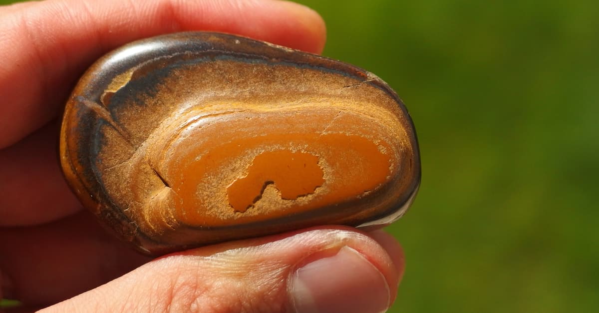 Tigers eye stone between thumb and finger