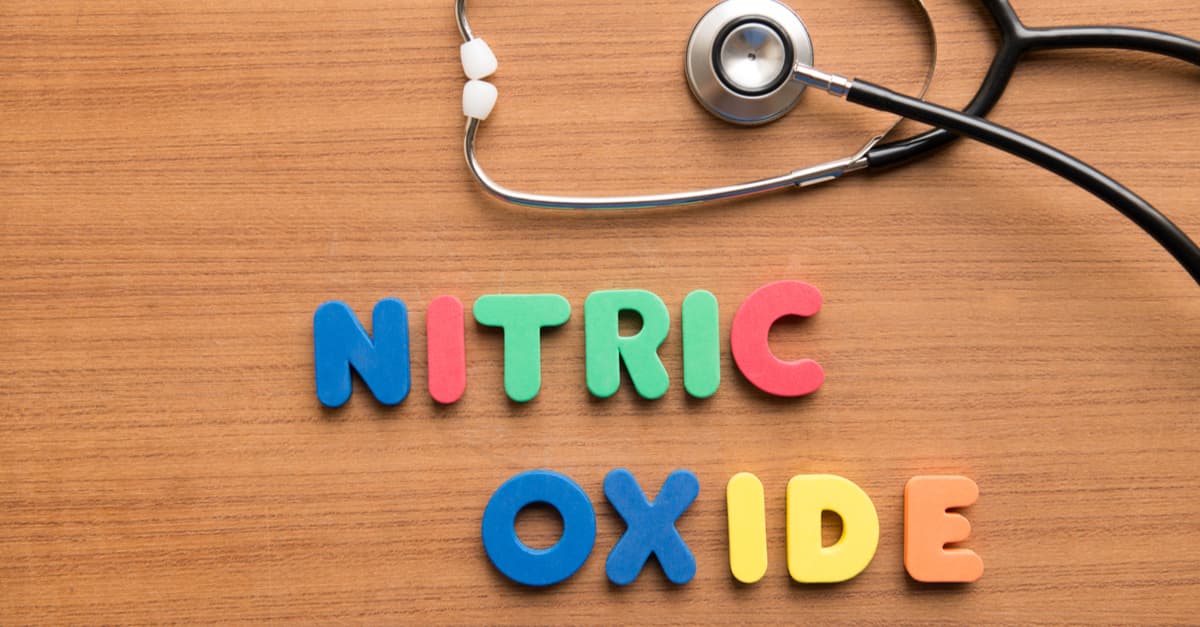 The words nitric oxide spelt out with childrens letters on a wooden table, beside a stethoscope