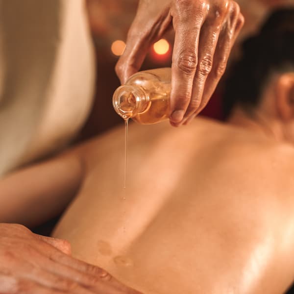 Woman getting oil on her back during a chakra massage